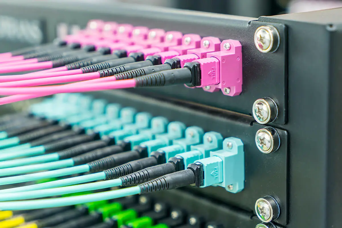 データセンターのパッチパネルに差し込まれたMPOファイバーコネクター