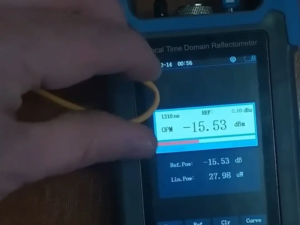 Câble à fibre optique courbé au-delà du rayon de courbure minimal, présentant une atténuation accrue sur le mesureur de puissance optique pendant les essais.