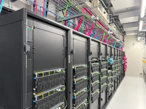 صف من حوامل خوادم GPU في مركز بيانات للذكاء الاصطناعي، مع حوامل كابلات علوية من شبكة سلكية تحمل كابلات منظمة ومميزة بألوان مختلفة